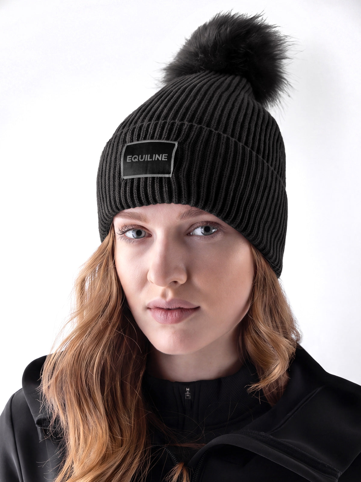 Equiline Ladies Eqcon Pom Pom Knitted Hat in Black, front view of the microfleece-lined knitted beanie with faux fur pom pom and Equiline logo patch.