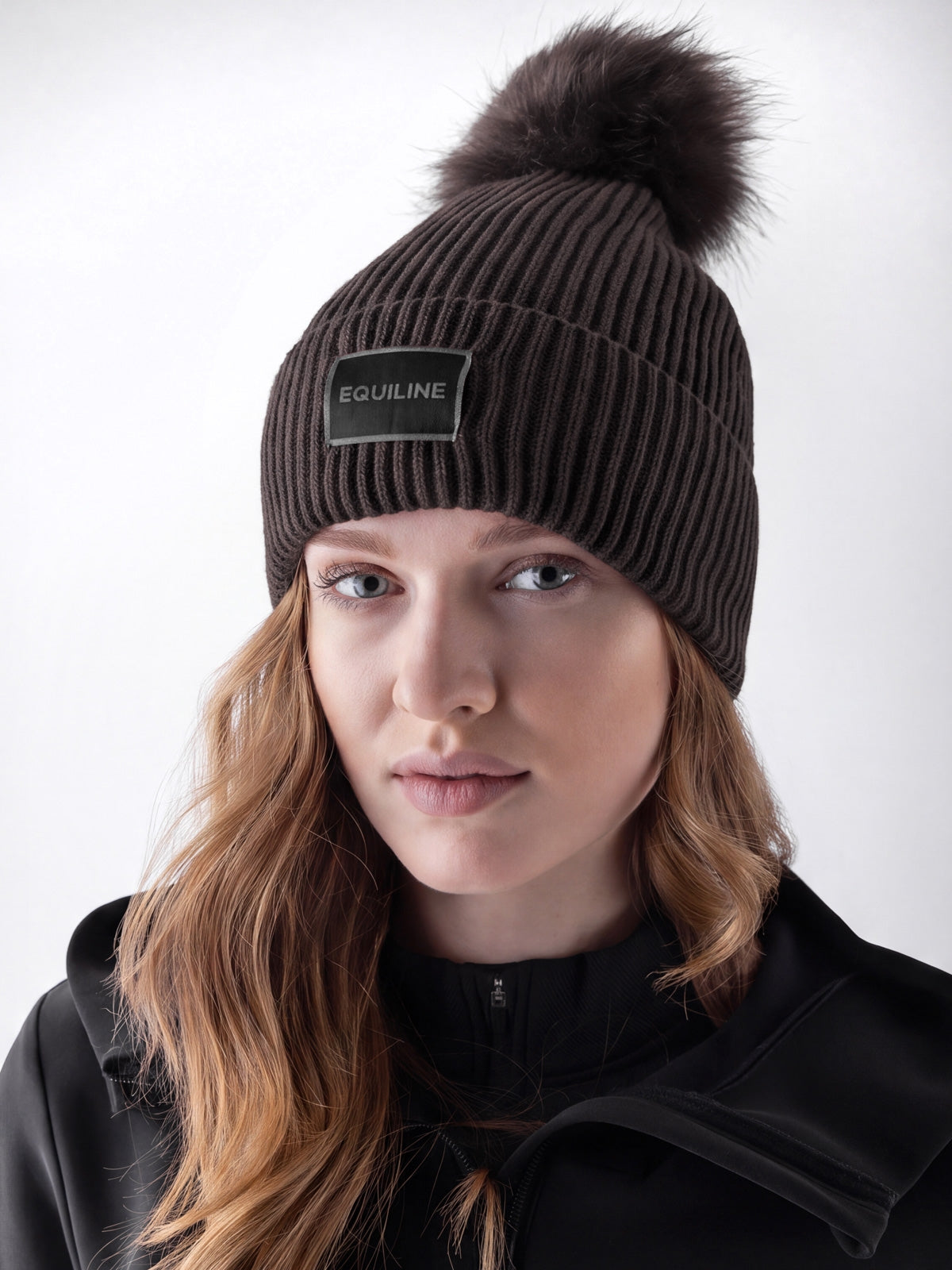 Equiline Ladies Eqcon Pom Pom Knitted Hat in Coffee Bean, shown worn, the microfleece-lined knitted beanie with faux fur pom pom and Equiline logo patch.