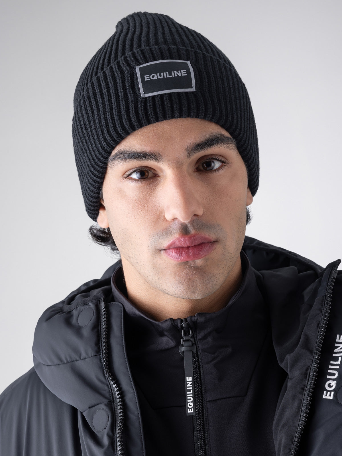 Equiline Unisex Eqcap Knitted Hat in Black, detail view of the microfleece-lined knitted beanie with jacquard Equiline logo patch.