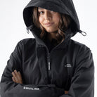 Equiline Ladies Eqextre black waterproof jacket worn with the adjustable hood up, showing the taped-seam water-tight construction.
