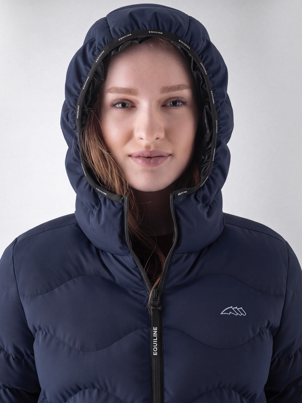 Equiline Ladies Eqcentry Padded Jacket in Blue, detail view of the hooded Eco-Duvet padded jacket with printed Equiline logo on the chest.